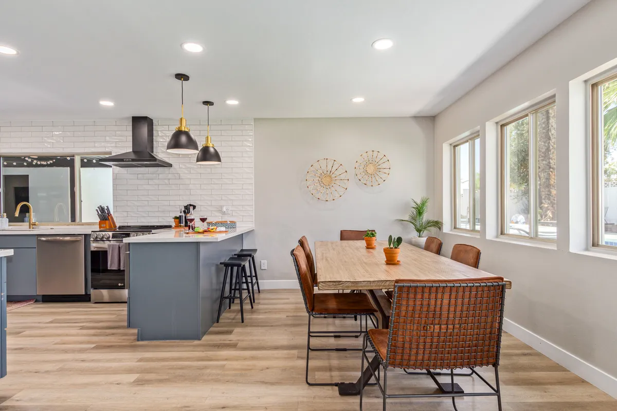 An open-concept kitchen and dining area showcasing a generous kitchen island, an elegant dining table, pendant lighting, and tasteful wall décor. The space is set for family gatherings, entertaining, and celebratory meals, radiating warmth and hospitality.